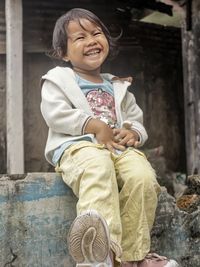 Portrait of smiling young woman sitting on footpath