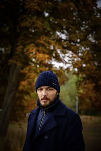 Portrait of man standing against trees in winter