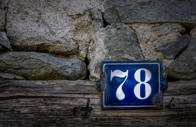 Close-up of sign on rock against wall