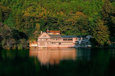 Built structure by lake against trees and plants