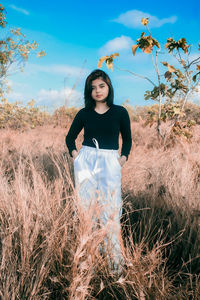 Portrait of woman standing on field against sky