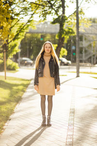 Portrait of young woman standing on footpath