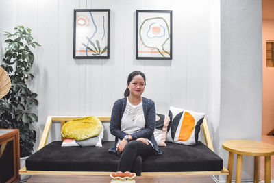 Portrait of young woman smiling while sitting on sofa at home