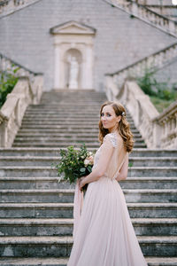 Young woman standing against building