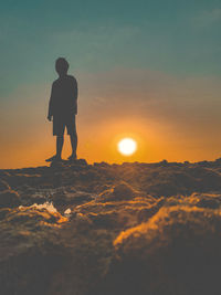 Rear view of silhouette man standing on mountain against sky during sunset