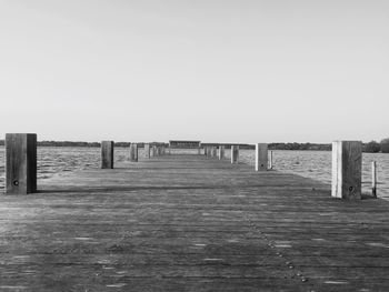 Wooden pier on sea against clear sky