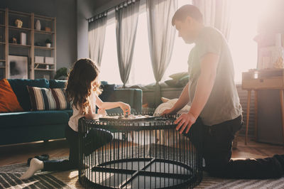 Girl playing checkers with father on table at home