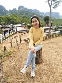 Portrait of smiling young woman standing against trees