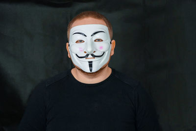 Portrait of man wearing mask against black backdrop