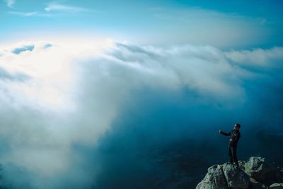 Man standing on rock against sky