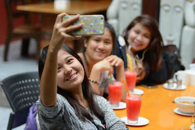 Portrait of smiling young woman using smart phone on table