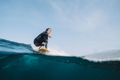 Split image of female surfer in wetsuit surfing on a longboard