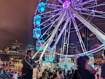 People in amusement park ride against sky at night