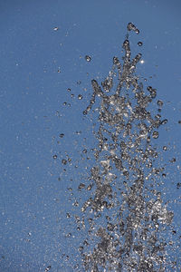 Close-up of water drops on leaf against blue sky