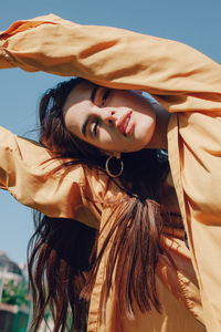 Portrait of young woman standing against blue sky