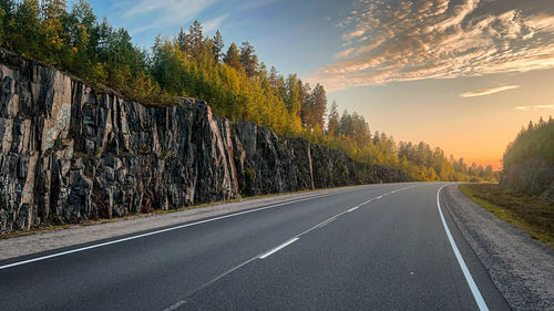 Road amidst trees against sky during sunset