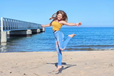 Full length of young woman standing on beach