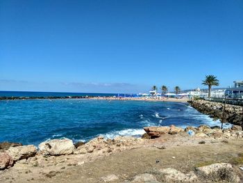 Scenic view of beach against clear blue sky