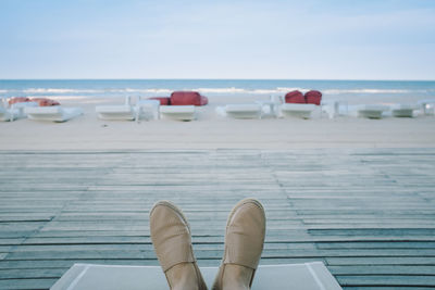 Low section of person wearing shoes on boardwalk at beach