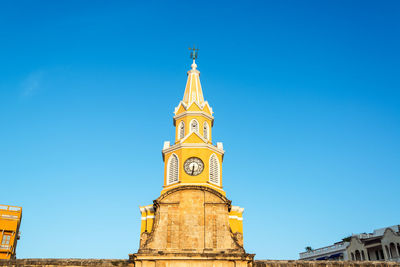 Low angle view of clock tower against clear blue sky