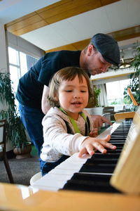 Girl playing piano by father at home