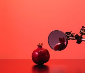 Pomegranate and mirror against red background