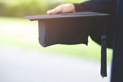 Midsection of student holding mortarboard