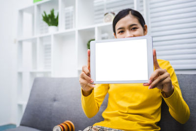 Woman using mobile phone while sitting on sofa at home