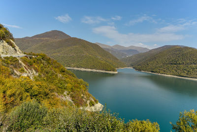 Scenic view of lake by mountains against sky