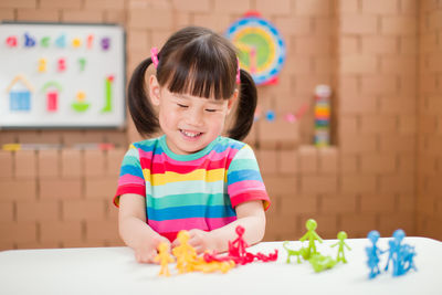 Cute girl holding multi colored ball on table