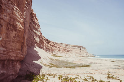 Rock formations on beach against sky