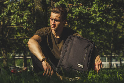 Young man looking away while sitting outdoors