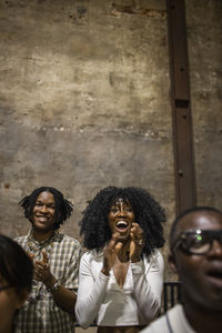 Excited curly haired woman cheering while watching play in stage theater