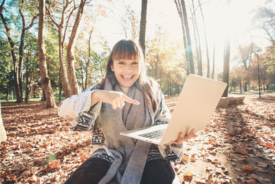 Young woman using laptop while sitting in forest