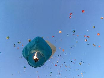 Low angle view of balloons flying against blue sky