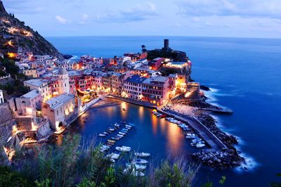 High angle view of illuminated buildings in city by sea