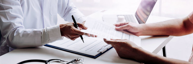 Midsection of man holding paper at home