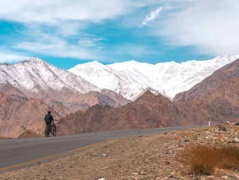 Rear view of man with bicycle by mountains