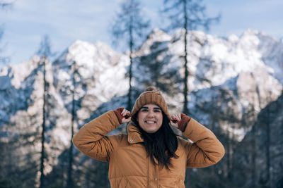 Portrait of young woman standing against trees