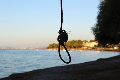 Close-up of silhouette rope on beach against clear sky