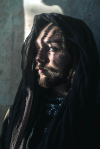 Close-up of handsome bearded man wearing scarf against wall