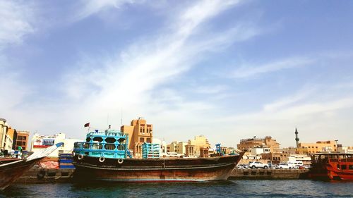 Boats moored in sea against sky in city