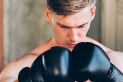 Close-up of confident young woman with boxing gloves in gym