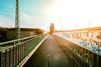 Footbridge in city against sky during sunset