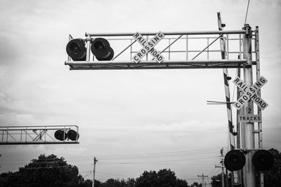 Low angle view of railroad crossing against sky