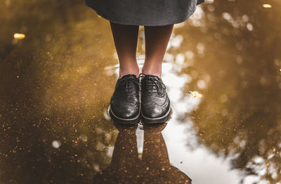 Low section of girl standing on puddle