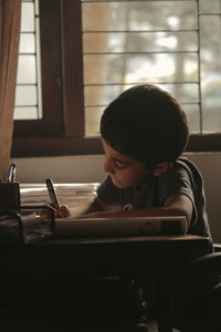 Boy sitting on table at home