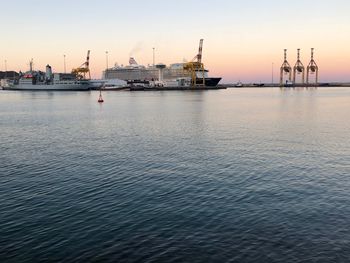Commercial dock by sea against sky during sunset
