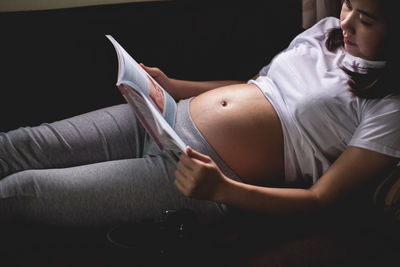 Midsection of woman lying down against black background