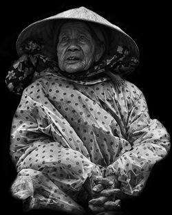 Woman with hands clasped standing against black background